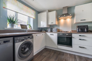 Modern kitchen with white cabinets, appliances and wood-effect floor.