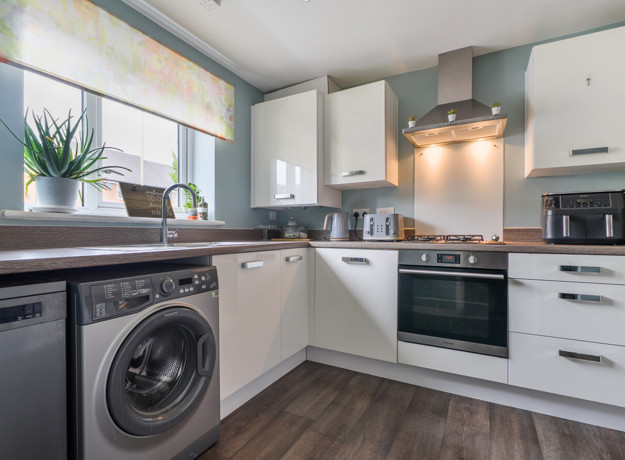 Modern kitchen with white cabinets, appliances and wood-effect floor.