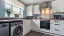 Modern kitchen with white cabinets, appliances and wood-effect floor.