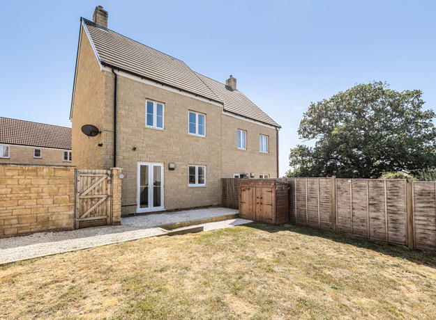 Rear garden with lawn and fenced boundaries behind the house.