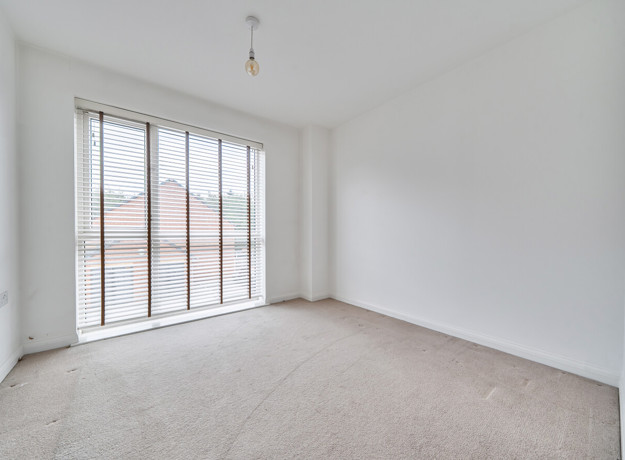 Bedroom with carpeted floor and large floor-to-ceiling window.