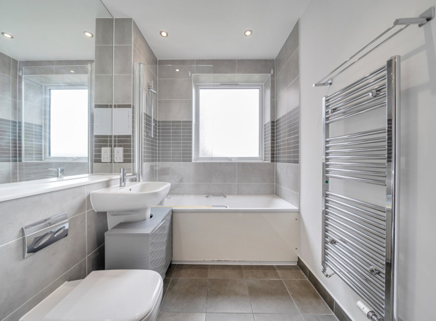 Contemporary bathroom with bathtub, overhead shower, toilet, sink, and grey wall tiles