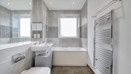 Contemporary bathroom with bathtub, overhead shower, toilet, sink, and grey wall tiles