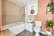 Bathroom with a bathtub, shower, toilet, sink, house plants and wall mirror.