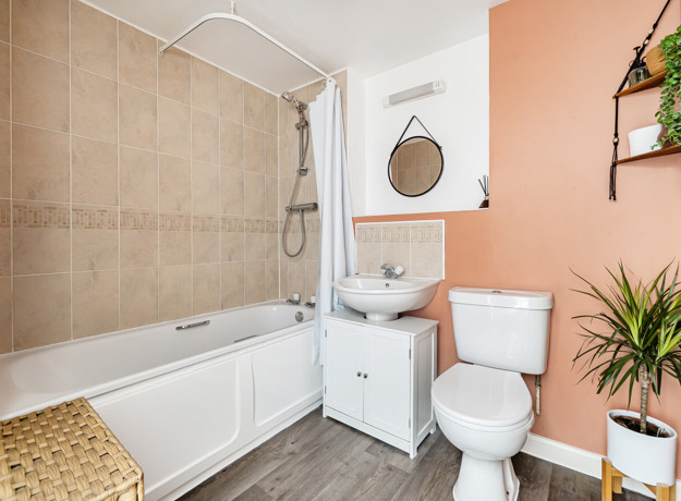 Bathroom with a bathtub, shower, toilet, sink, house plants and wall mirror.