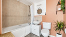 Bathroom with a bathtub, shower, toilet, sink, house plants and wall mirror.