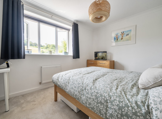 Bedroom with a double bed, bedside furniture and a window.
