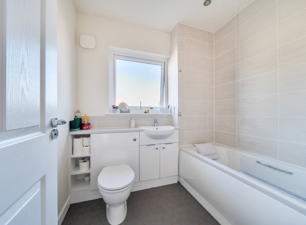 Bathroom with toilet, sink, bathtub and frosted window.