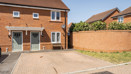 Semi detached brick house with white windows, green front door and driveway