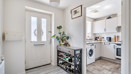 Entry hallway with a door, shelving unit and access to the kitchen.