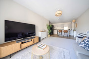 Living room with sofa, TV, coffee table and open-plan kitchen and dining area.
