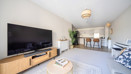 Living room with sofa, TV, coffee table and open-plan kitchen and dining area.