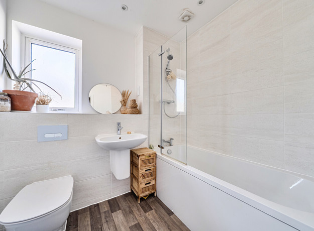 Bathroom with bath, shower, toilet, sink and frosted window.
