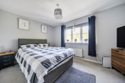 Bedroom with double bed, chest of drawers, and window with curtains.