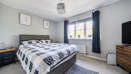 Bedroom with double bed, chest of drawers, and window with curtains.