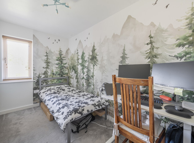 Bedroom with single bed, desk, computer setup and feature wall mural