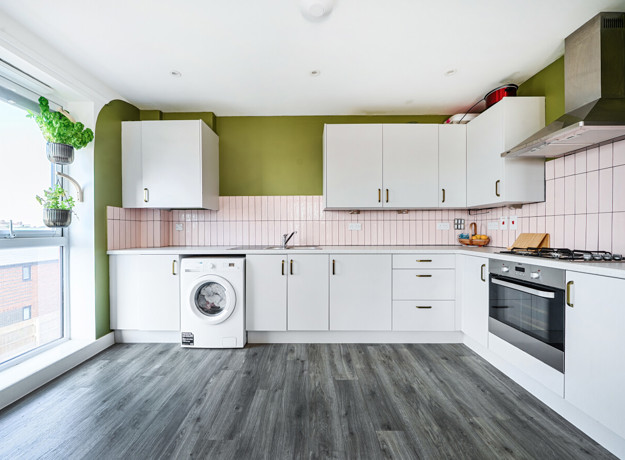 Kitchen with cabinets, oven, washing machine, and countertop appliances.