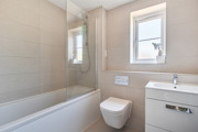 Bathroom with bathtub, shower screen, toilet, sink and frosted window.