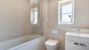 Bathroom with bathtub, shower screen, toilet, sink and frosted window.