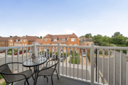 Balcony with outdoor table and chairs overlooking nearby buildings and rooftops.