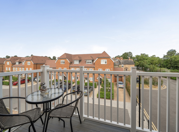 Balcony with outdoor table and chairs overlooking nearby buildings and rooftops.