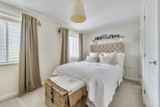 Bedroom with a double bed, bedside tables, curtains and a wicker basket.