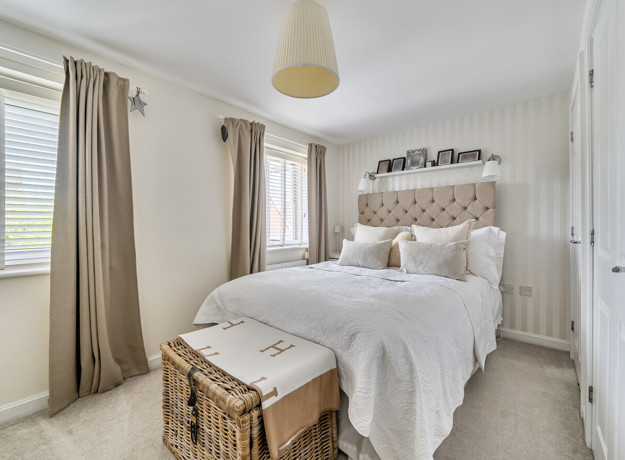Bedroom with a double bed, bedside tables, curtains and a wicker basket.