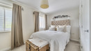 Bedroom with a double bed, bedside tables, curtains and a wicker basket.