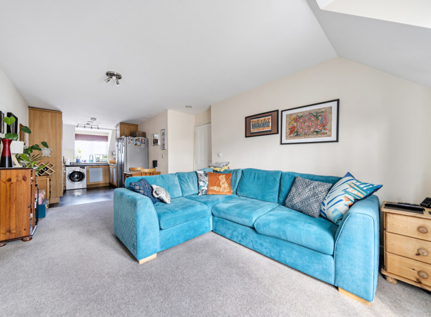 Open-plan living and dining area with blue sofa and kitchen.