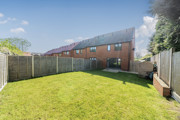 Enclosed rear garden with lawn, fenced boundaries and brick houses beyond