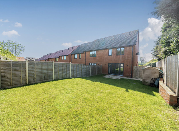 Enclosed rear garden with lawn, fenced boundaries and brick houses beyond