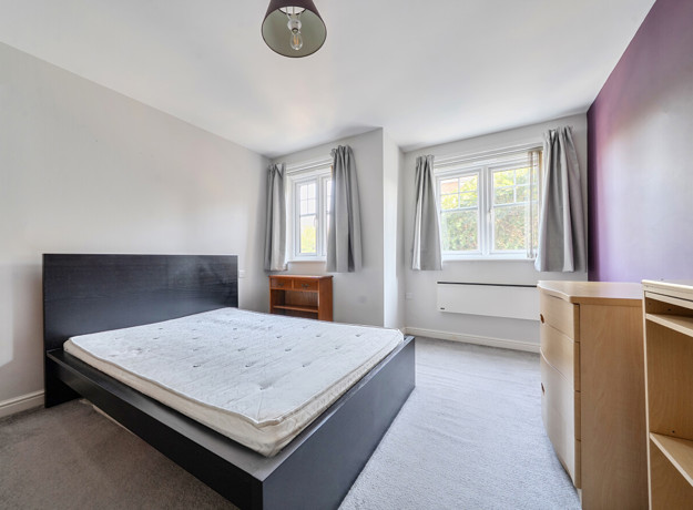 Bedroom with double bed, desk, drawers and window.