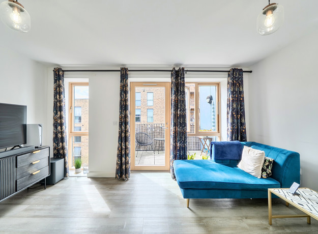 Living room with blue sofa and doors opening to a balcony.