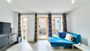 Living room with blue sofa and doors opening to a balcony.
