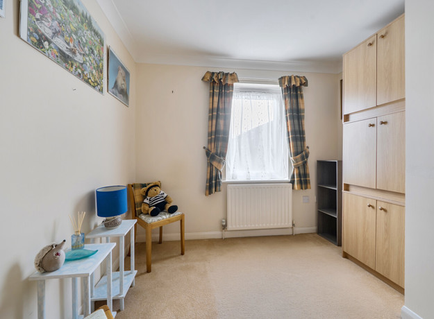 Bedroom with wardrobes, chair, desk and window.