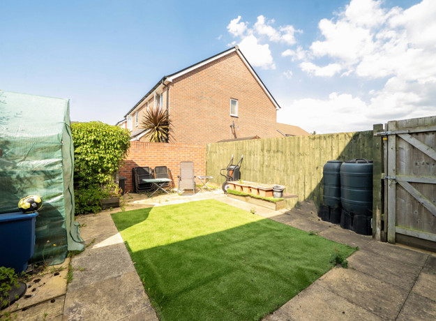 Enclosed rear garden with a lawn, fencing, side gate and neighbouring houses.