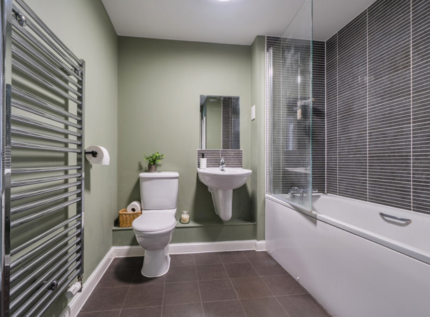 Bathroom with bathtub, shower, toilet, sink and heated towel rail.