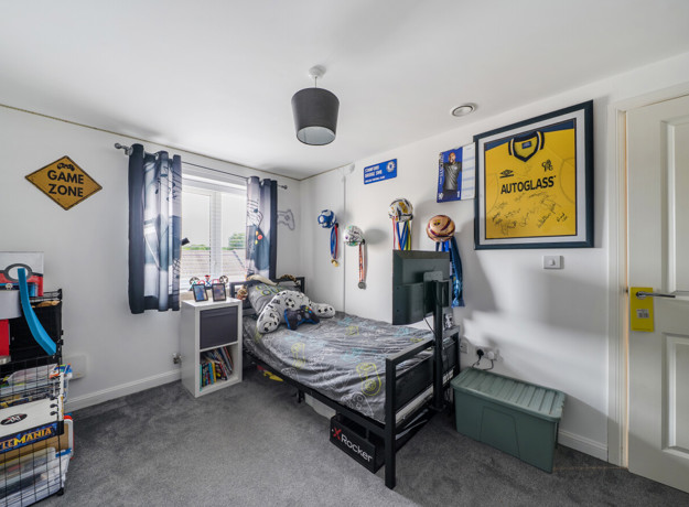 Bedroom with single bed, posters and storage shelves.