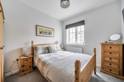 Bedroom with wooden bed frame, drawers, and window with blinds.