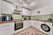Kitchen with fitted cabinets, oven, washing machine and worktops.