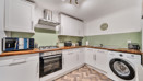 Kitchen with fitted cabinets, oven, washing machine and worktops.
