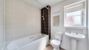 Bathroom with bath, toilet and pedestal sink.