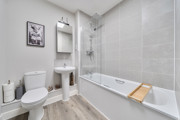Bathroom with bathtub, shower, toilet, sink, and shelving.