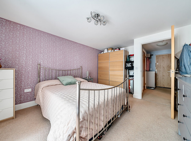 Bedroom with double bed, wardrobes and chest of drawers.