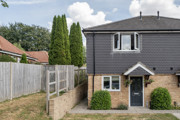 A two-storey semi-detached house with a fenced side path and shrubs.