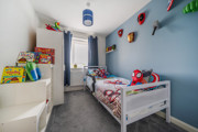 Children's bedroom with single bed, toys, shelves and blue walls.