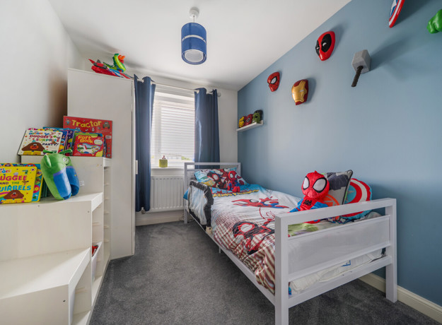 Children's bedroom with single bed, toys, shelves and blue walls.
