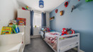 Children's bedroom with single bed, toys, shelves and blue walls.