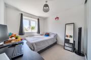 Bedroom with bed, desk, large mirror and neutral décor