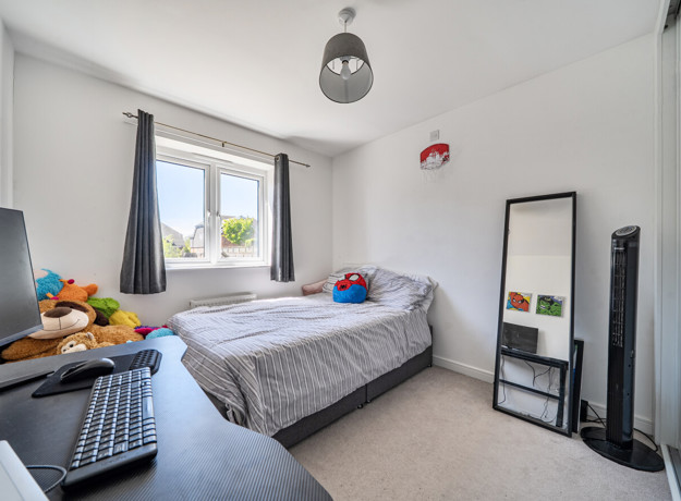 Bedroom with bed, desk, large mirror and neutral décor